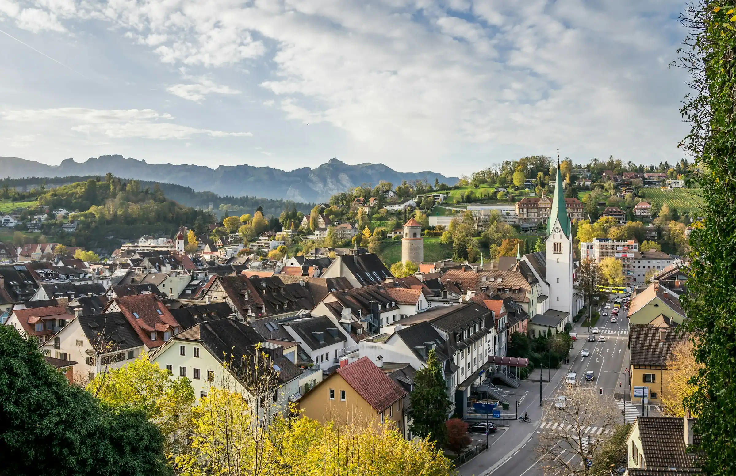 Blick über [Nachbarort A] mit Kirche und Bergen [eigenes Ortsfoto einsetzen]